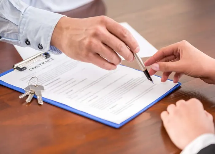 Young woman is signing financial contract with male realtor. Close-up.