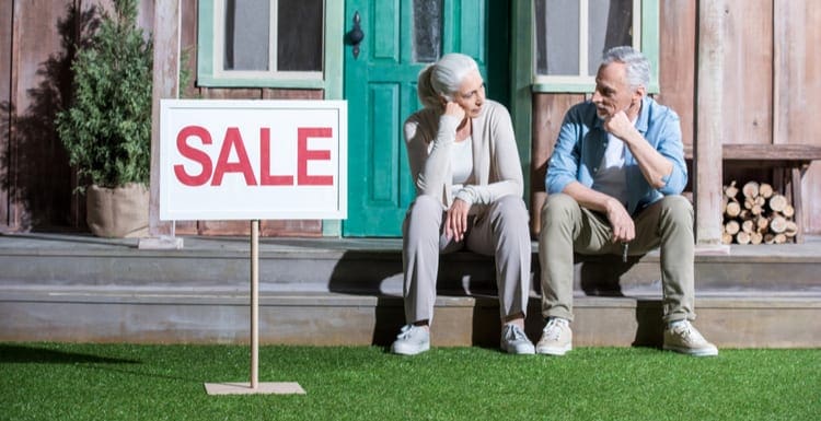 As an image for a piece on for sale by owner homes, upset senior couple sitting on porch and selling their house, house for sale concept