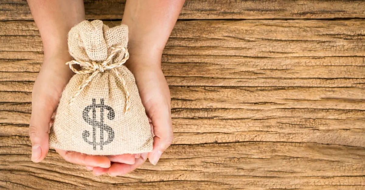 Women hold a money bag on the vintage wood background, a loan or saving money for future investment concept.