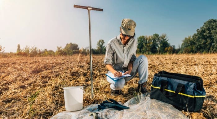 Soil perc test. Female agronomist taking notes in the field. Environmental protection, organic soil certification, research