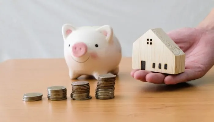 Men hand giving wood house beside increasing money, coin stack on wood table with piggy bank. Saving plan to buy property, house. Personal financial concept for own a house. with copy space for text
