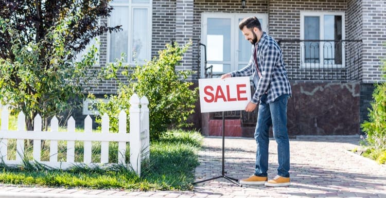 As an image for a piece on how to sell your house, young man with sale board selling his house