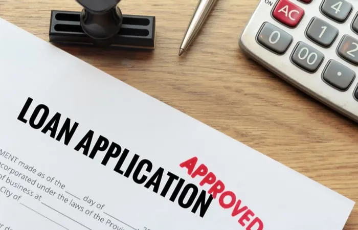 Approved loan application with rubber stamp and calculator concept