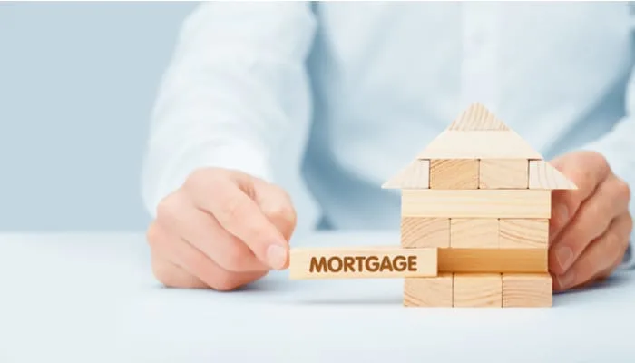 As an image for a piece on hard money loans, Mortgage concept. Financial agent complete wooden model of the house with last piece with text mortgage.