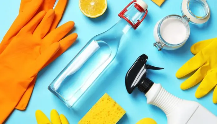 Flat lay composition with vinegar and cleaning supplies on color background to remove hard water stains from toilets