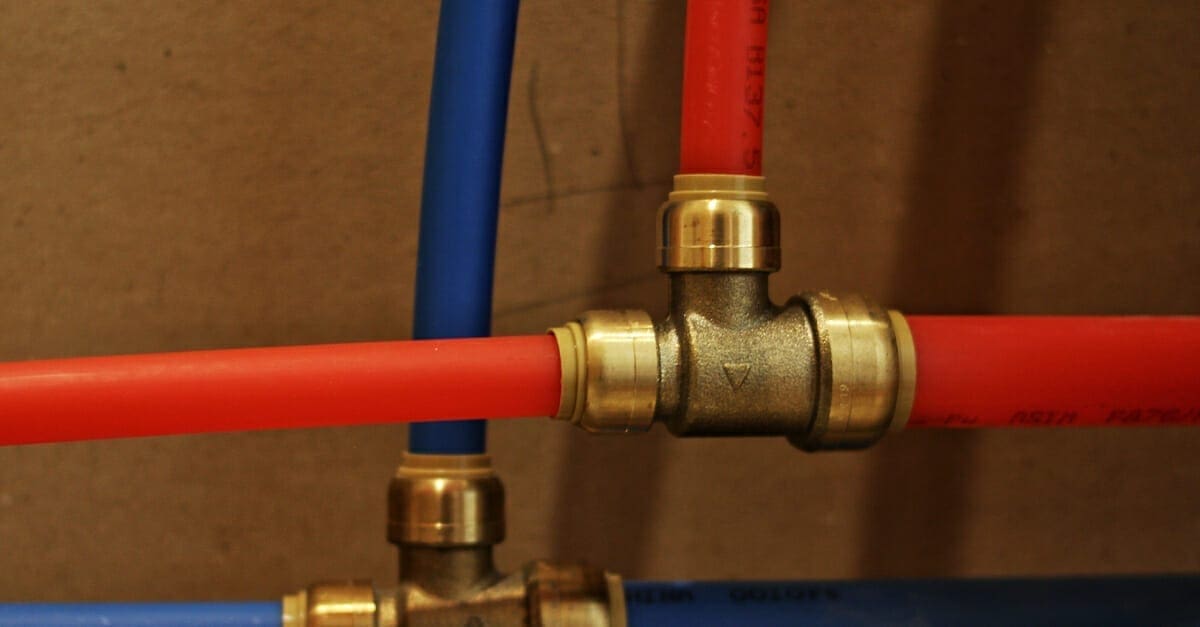 Pex pipe in red and blue feeding into a copper fitting with some hose clamps