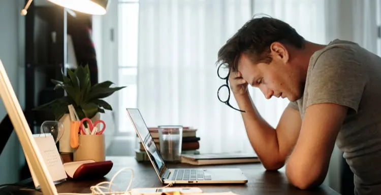 Man stressed while working on laptop as the featured image for a piece on why is rent so high
