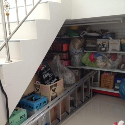 A group of items sit on useful shelving under a staircase