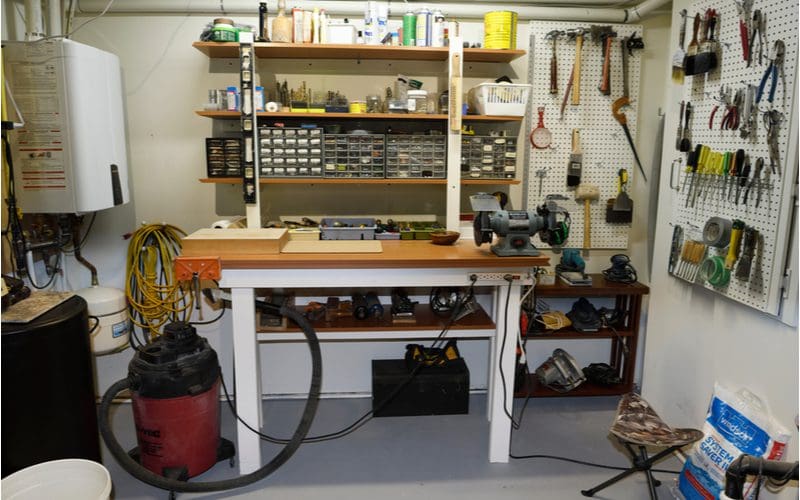 Image of an unfinished basement with a workbench and pegboard on the walls
