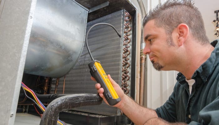 An Hvac technician searching for a refrigerant leak on an evaporator coil.