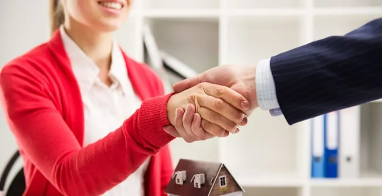Two business people shaking hands as successful agreement in real estate agency office. Concept of housing purchase and insurance for a piece on a Texas real estate license