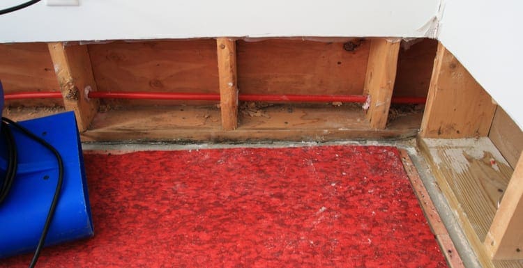 As the featured image for a piece on how to dry carpet, an industrial fan drying water damaged wall and carpet padding in a residential basement