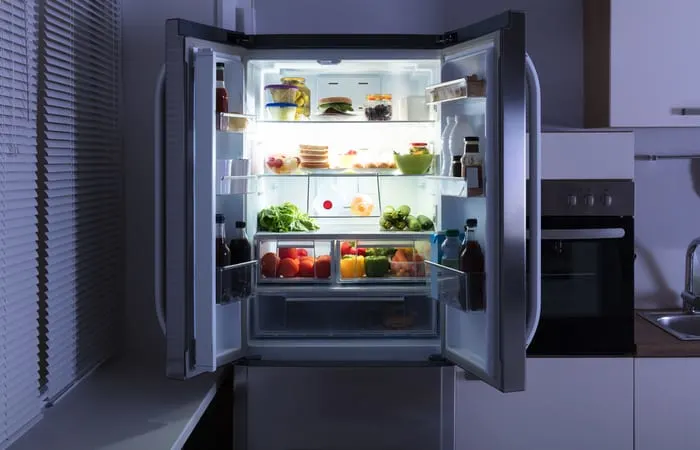 Open Refrigerator Full Of Juice And Fresh Vegetables In Kitchen as an image for a piece on refrigerator dimensions