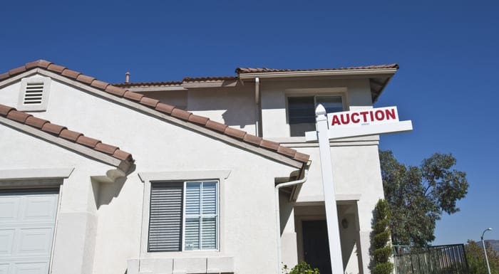 A house from a tax deed investment auction with 'Auction Sign' against blue sky