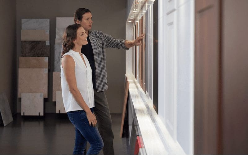 Couple standing in a showroom debating kitchen cabinet dimensions