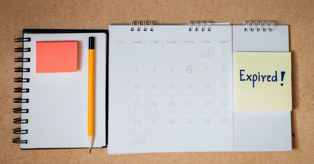 A notepad on which sits a sticky note and a pencil and next to it is a calendar with a sticky note that says 