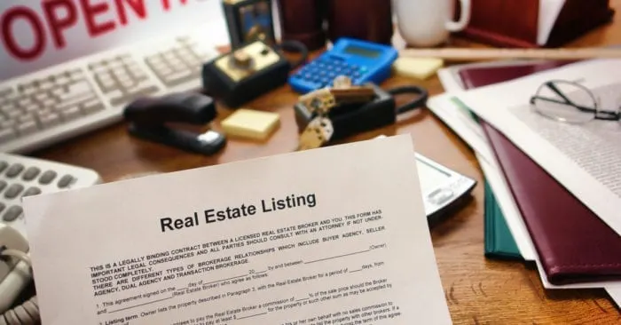 Real estate broker listing contract over busy Realtor desk in realty agent resale office (fictitious document with authentic legal language)