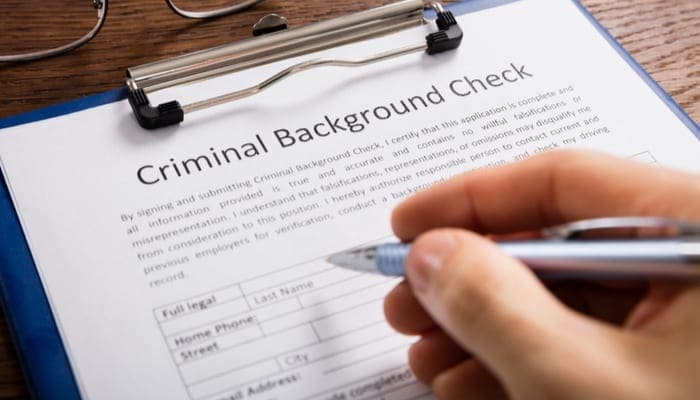 Close-up Of Person Hand Filling Criminal Background Check Application Form as a piece on an Ohio real estate license application
