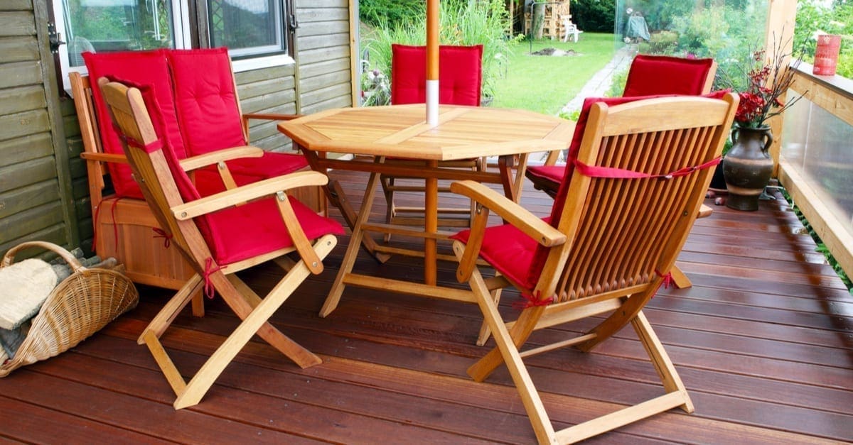 Photo of a spacious brown partially covered deck featuring Acacia Wood patio furniture covered in red cushions