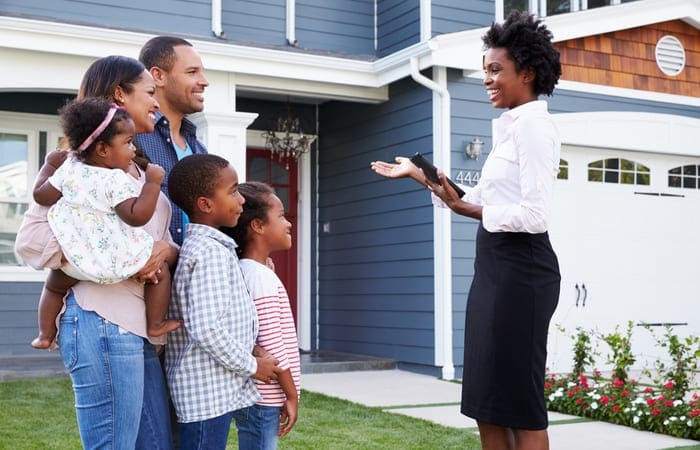 Real estate agent showing a family a house, closer in as the image for a piece on a real estate agent job description