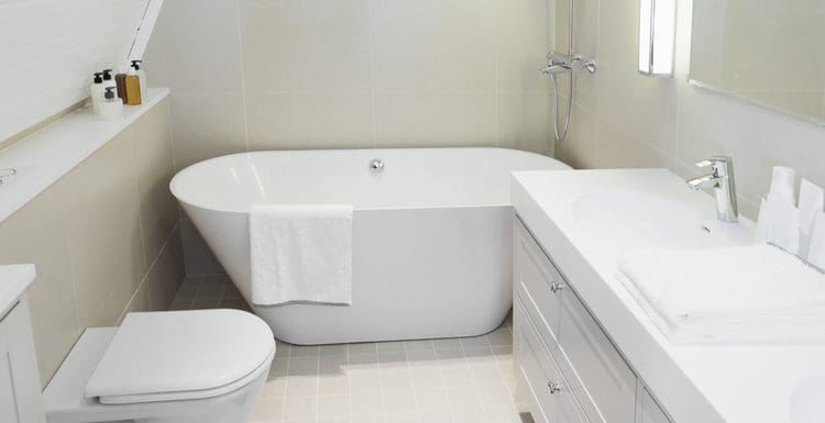 Featured image for a piece on small bathtubs that depicts such a fixture on light green tile flooring