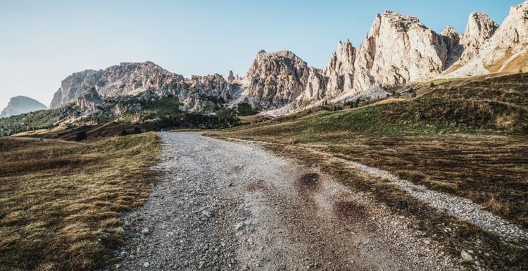 Dirt road and hiking trail track in Dolomites mountain, Italy, in front of Pizes de Cir Ridge mountain ranges in Bolzano, South Tyrol, Northwestern Dolomites, Italy as an image for a piece on how to buy land