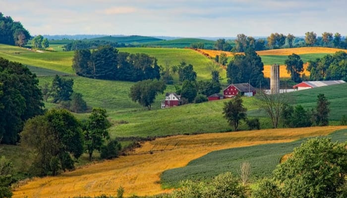 A bunch of farmland with a farmhouse and barn on it as a piece for how to buy land