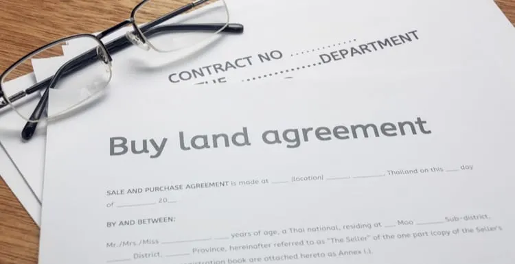 pen and land contract form on wood background.Business buy and sell home concept.