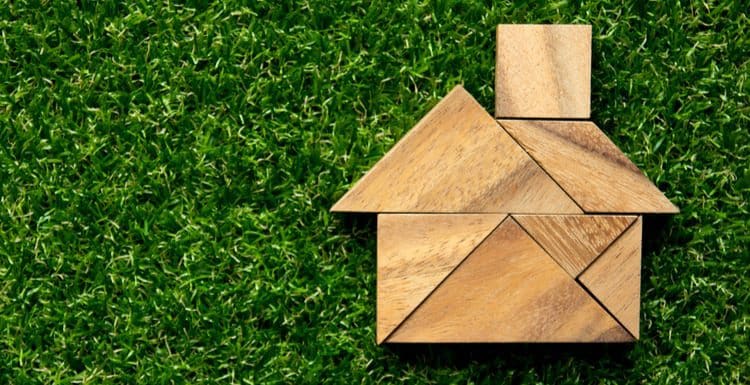Tangram puzzle in home shape on artificial green grass background (Concept for dream home as the featured image for a piece on a MyHouseDeals review