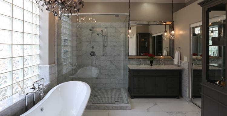 A luxury master bathroom complete with handing chandelier and a clear shower door along with a white tub as the featured image for a piece on BathWraps