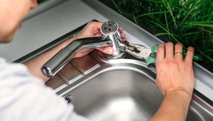 Plumber repairing the faucet of a sink in kitchen, man repair and fixing leaky old faucet, cartridge or mixer of the faucet, concept of repair and technical assistance