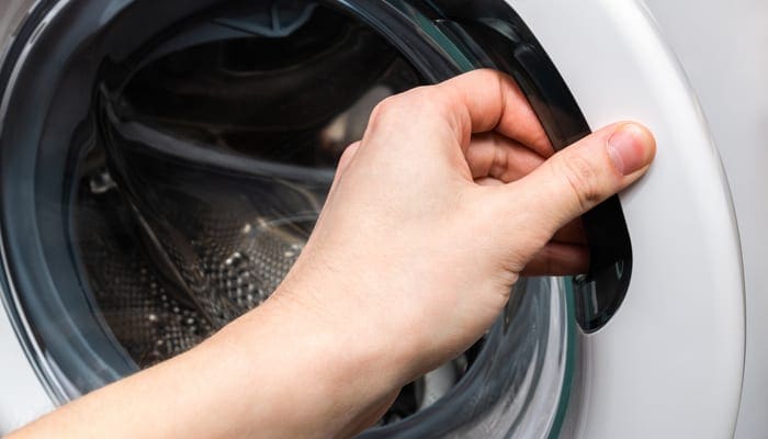 Washing machine. Hand opens washing machine lid. Do laundry concept