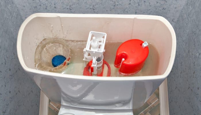 Blue cleaning water-soluble tablet falls into the water drain the toilet tank contributing to a slow flushing toilet