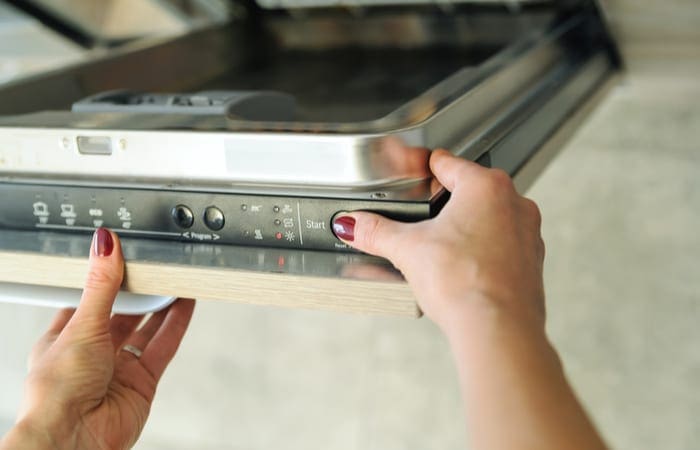 Run the dishwasher machine. Woman's finger pressing the Start button.