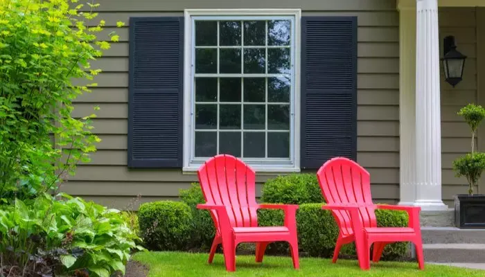 As an image for a piece on how to improve curb appeal,Red outdoor chairs on green grass lawn of house manicured front yard