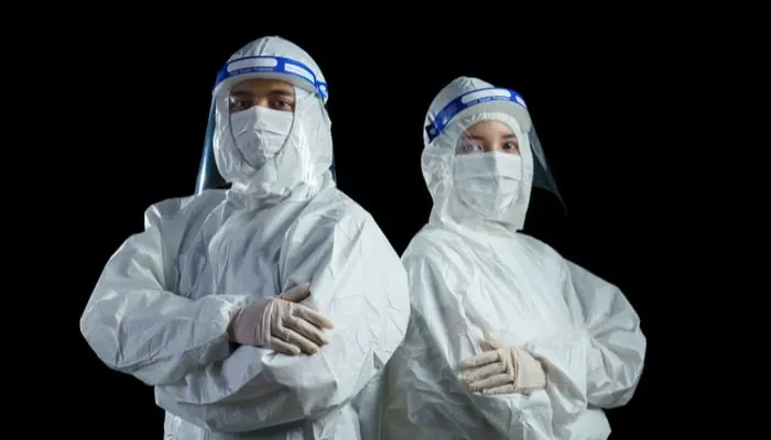 Two mold remediation professionals standing back to back with arms crossed preparing to handle a white mold outbreak
