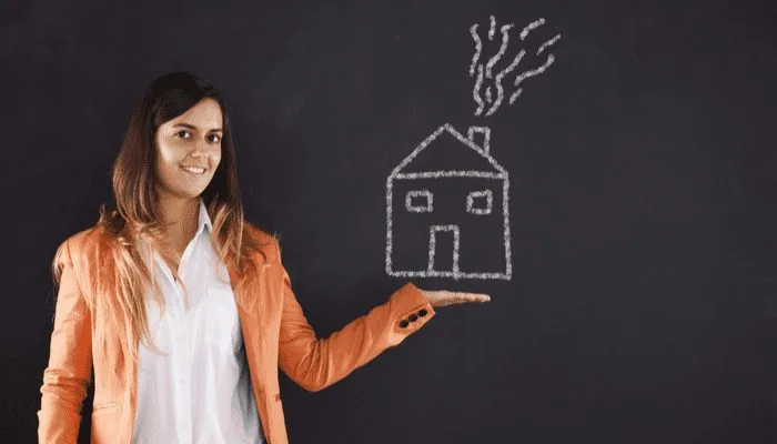 Happy woman showing a house drawing in the chalkboard