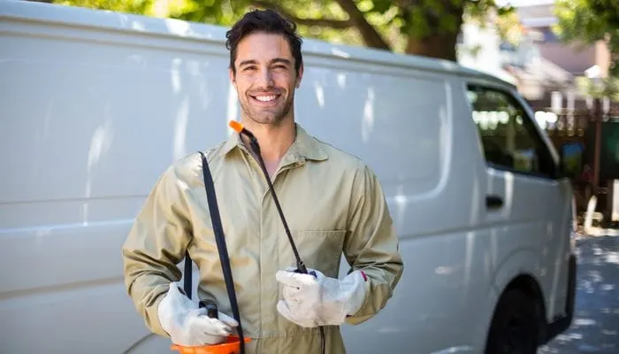Portrait of smiling worker with pesticide sprayer while standing by van