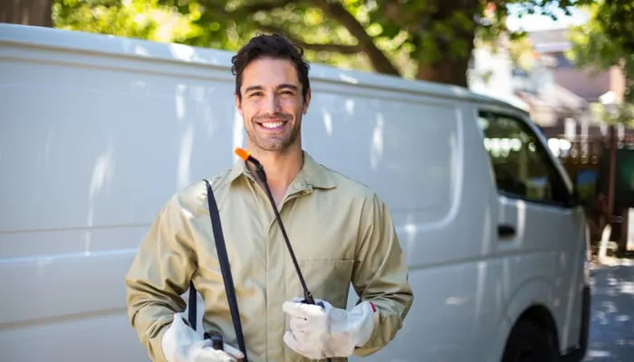Portrait of smiling worker with pesticide sprayer while standing by van