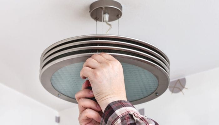 Electrician fixes round ceiling light in room