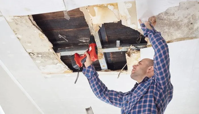 Man repairing collapsed ceiling. Ceiling panels damaged huge hole in roof from rainwater leakage.Water damaged ceiling .