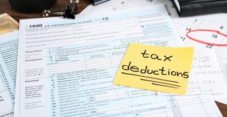 To symbolize an answer to the question ARE HOME IMPROVEMENTS TAX DEDUCTIBLE, Paper sheet with text TAX DEDUCTIONS and individual tax return form on table