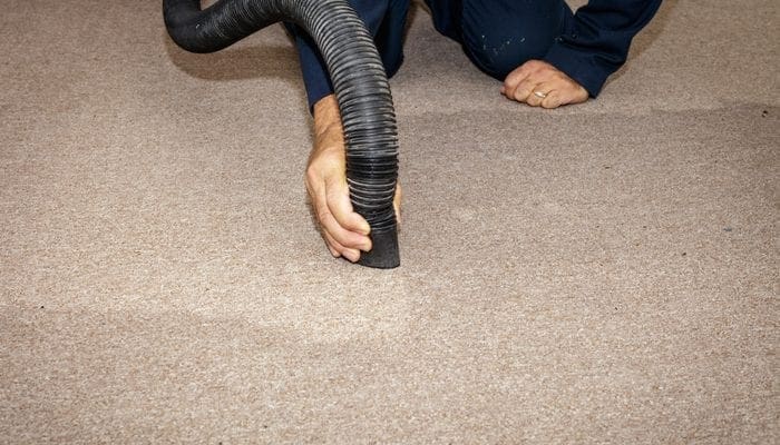 Using a wet/dry vac to remove water from a carpet after a pipe burst.