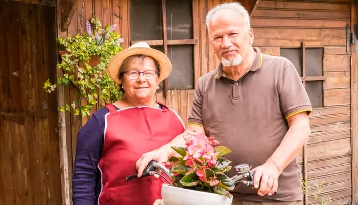 happy and cheerful senior couple enojy the outdoor leisure activity at the garden at home. wood tiny house in background and old bike. home work to have care of the house. retired concept