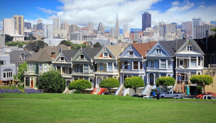 San Francisco, California, United States - city skyline with famous Painted Ladies, Victorian homes at Alamo Square (Western Addition neighborhood) and a row of patio homes