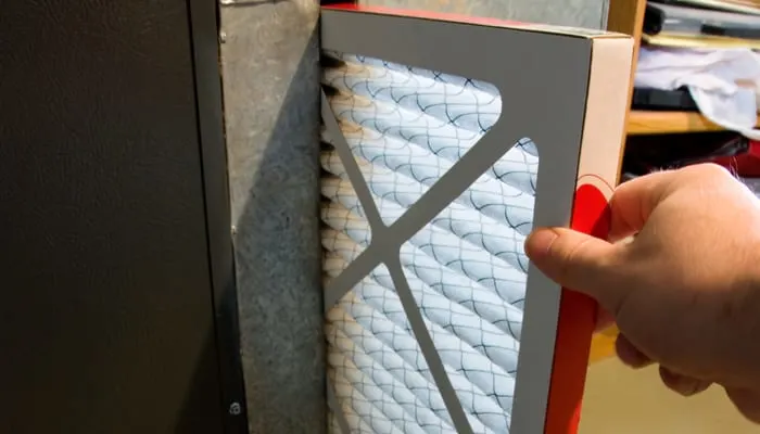 Close up of hand changing home furnace filter as an image for a piece on MERV ratings