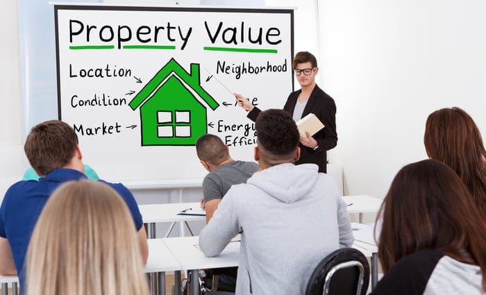 A Male Teacher Explaining The Concept Of Property Value Concept To Students In Classroom
