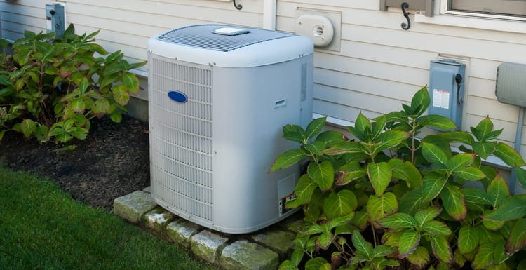 Heating and air conditioning inverter on the side of a house as a featured image for a piece on Carrier air conditioner prices