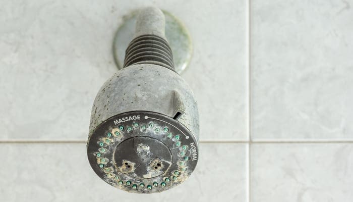 old shower head clogged with many limestone and dirty stain