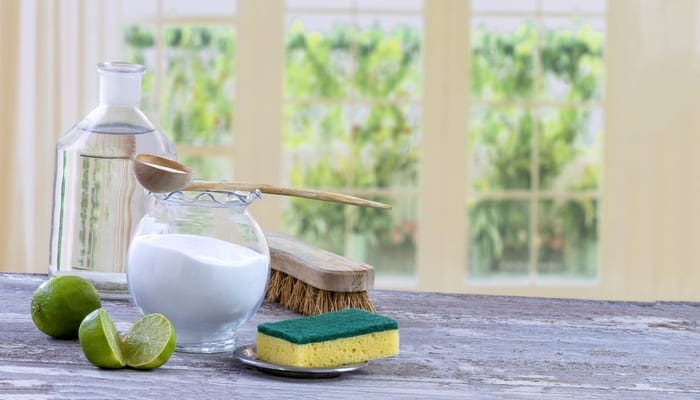 Eco-friendly natural cleaners baking soda, lemon and cloth on wooden table windows background as an image for a piece on how to unclog a shower drain
